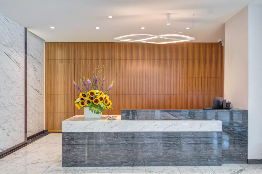 Concierge desk with florals in modern lobby.